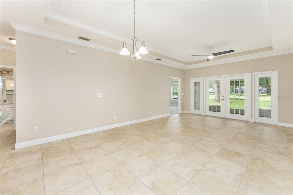 A spacious living room features beige walls, large floor tiles, a tray ceiling, and glass doors — 12705 NW 11TH PLACE, NEWBERRY, FL