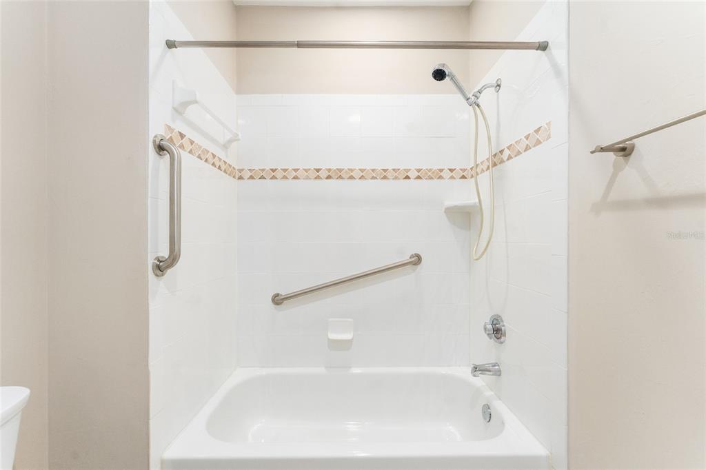 A white bathtub with a handheld showerhead and two safety grab bars on the wall — 12705 NW 11TH PLACE, NEWBERRY, FL