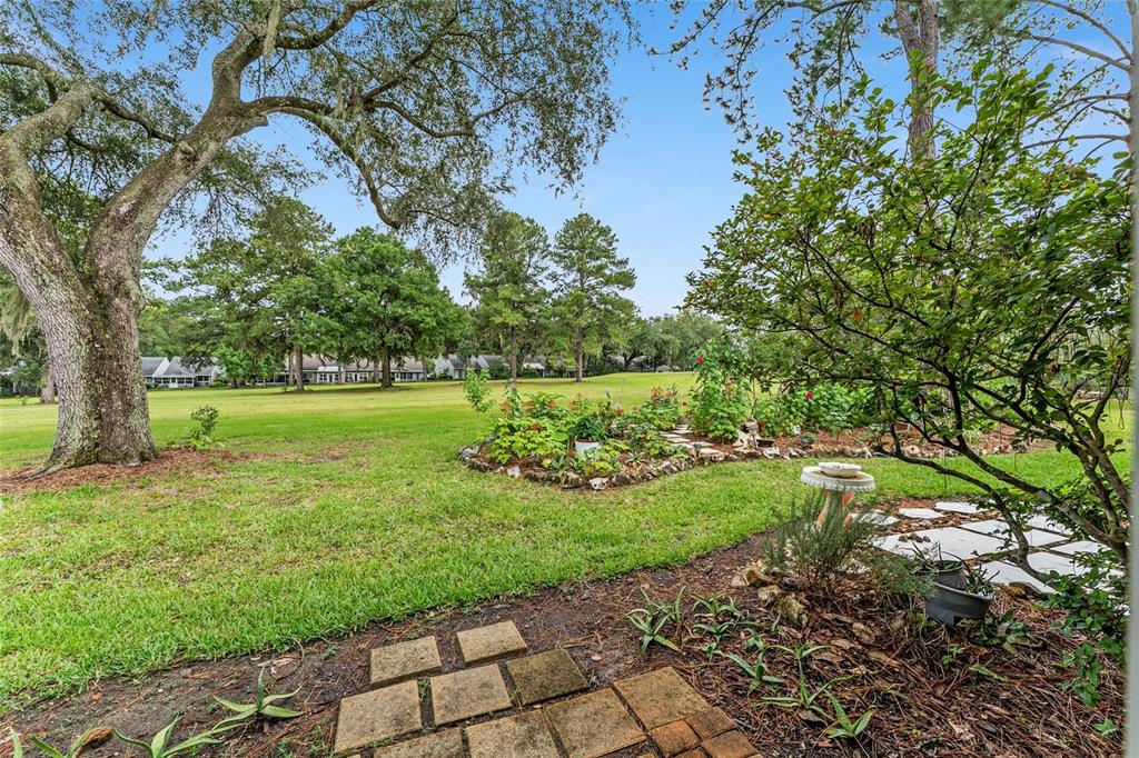 A backyard view features a stone patio, a garden bed, and a large grassy lawn — 12705 NW 11TH PLACE, NEWBERRY, FL