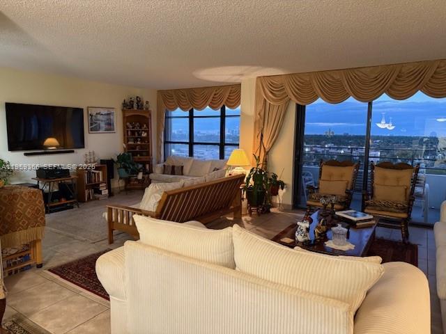 A living room features a large television, a wooden futon, and a view of the city — 600 Three Islands Blvd # 1004, Hallandale Beach FL 33009, HALLANDALE BEACH, FL