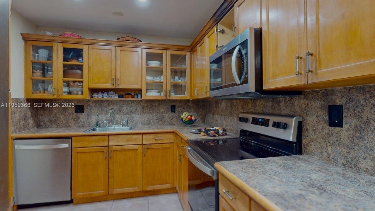 A kitchen features light wood cabinets, stainless steel appliances, and a speckled laminate countertop — 600 Three Islands Blvd # 1004, Hallandale Beach FL 33009, HALLANDALE BEACH, FL
