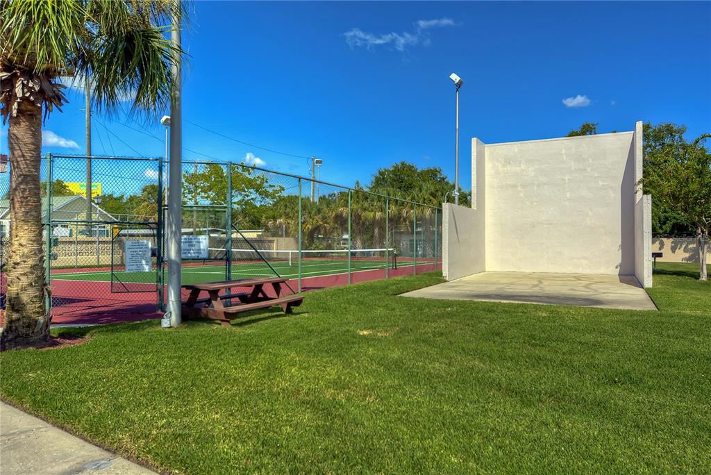 An outdoor handball court and a fenced tennis court sit on a grassy lawn — 9110 TUDOR DRIVE UNIT L106, TAMPA, FL