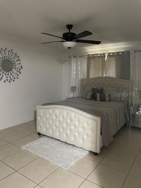 A bedroom features a tufted white bed, a ceiling fan, and tile flooring — 9110 TUDOR DRIVE UNIT L106, TAMPA, FL