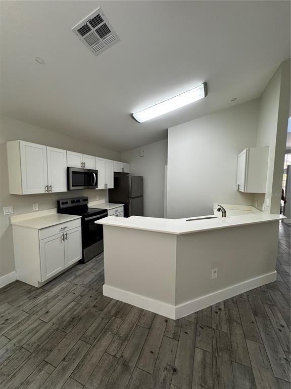A kitchen features white cabinets, stainless steel appliances, and a peninsula with a sink — 1645 17TH STREET SW, NAPLES, FL