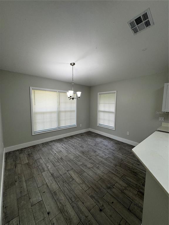 A dining area features gray wood-look tile flooring, light gray walls, and a hanging chandelier — 1645 17TH STREET SW, NAPLES, FL