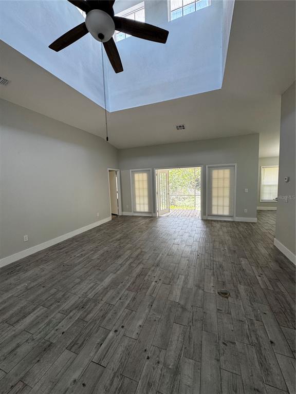 A spacious living room features high ceilings, a ceiling fan, and wood-look tile flooring — 1645 17TH STREET SW, NAPLES, FL