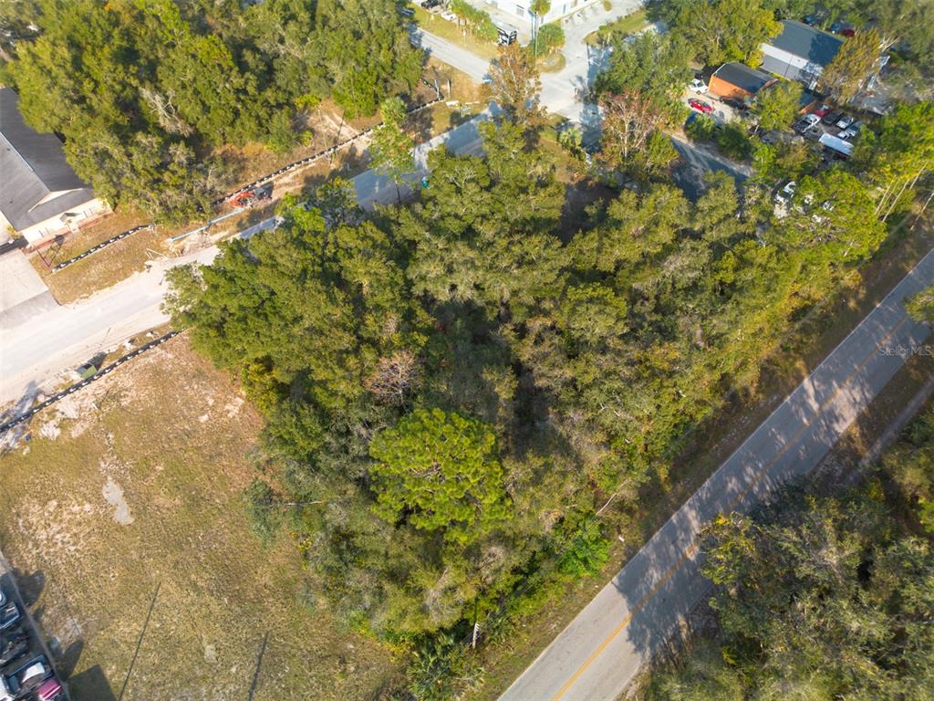 An aerial view shows a wooded, undeveloped lot situated between two paved roads — 290 S INDUSTRIAL DRIVE, ORANGE CITY, FL