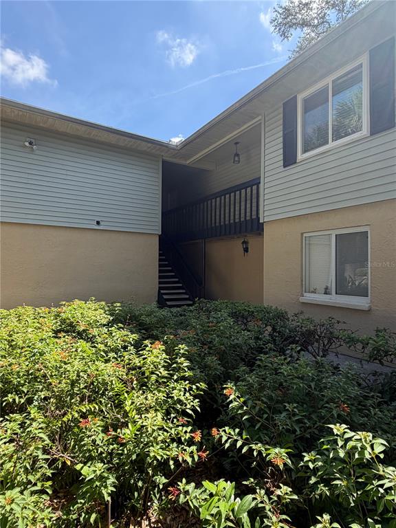 An exterior view of a two-story building with light-colored siding and a staircase — 233 THORN TREE PLACE, BRANDON, FL