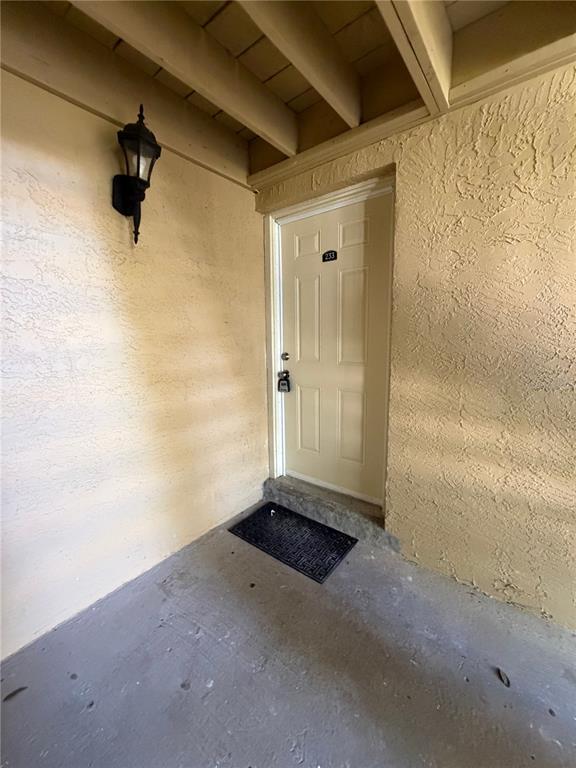 A beige exterior door with a lockbox and a wall-mounted light fixture on a porch — 233 THORN TREE PLACE, BRANDON, FL