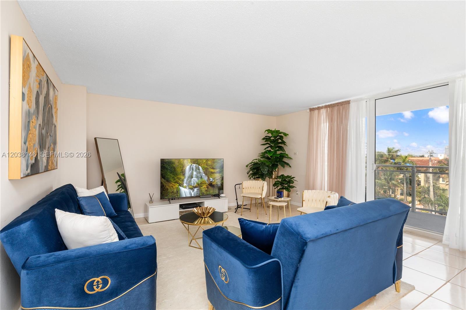 A living room features two blue velvet sofas, a television, and a balcony with views — 2030 S Ocean Dr # 307, Hallandale Beach FL 33009, HALLANDALE BEACH, FL