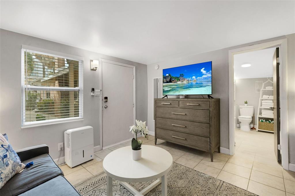 A living room features a sofa, a round coffee table, a dresser with a television, and tile flooring — 18 HEILWOOD STREET, CLEARWATER, FL
