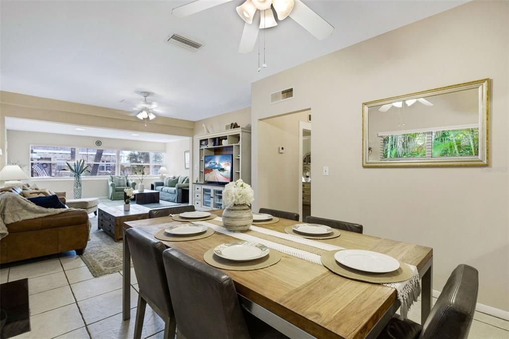 A dining area with a wooden table and chairs sits adjacent to a living room — 18 HEILWOOD STREET, CLEARWATER, FL