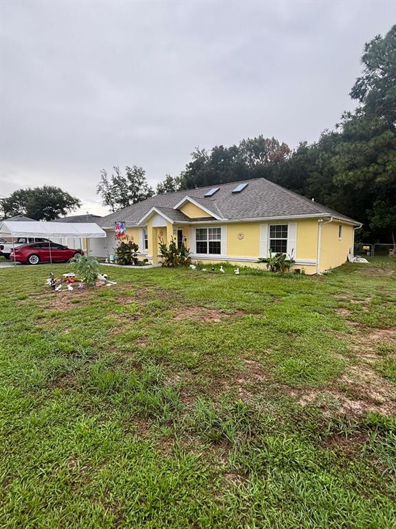 A yellow single-story house with a gray shingled roof and a white carport — 41 WATER TRACK DRIVE, OCALA, FL