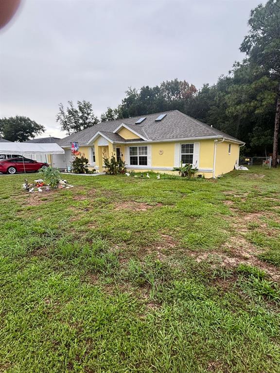 A yellow, single-story house with a gray shingled roof sits on a grassy lot — 41 WATER TRACK DRIVE, OCALA, FL
