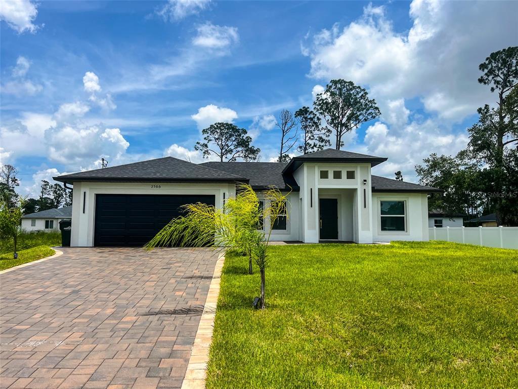 A modern, single-story white house with a dark garage door and a paved driveway — 2366 RIBBLE STREET, NORTH PORT, FL