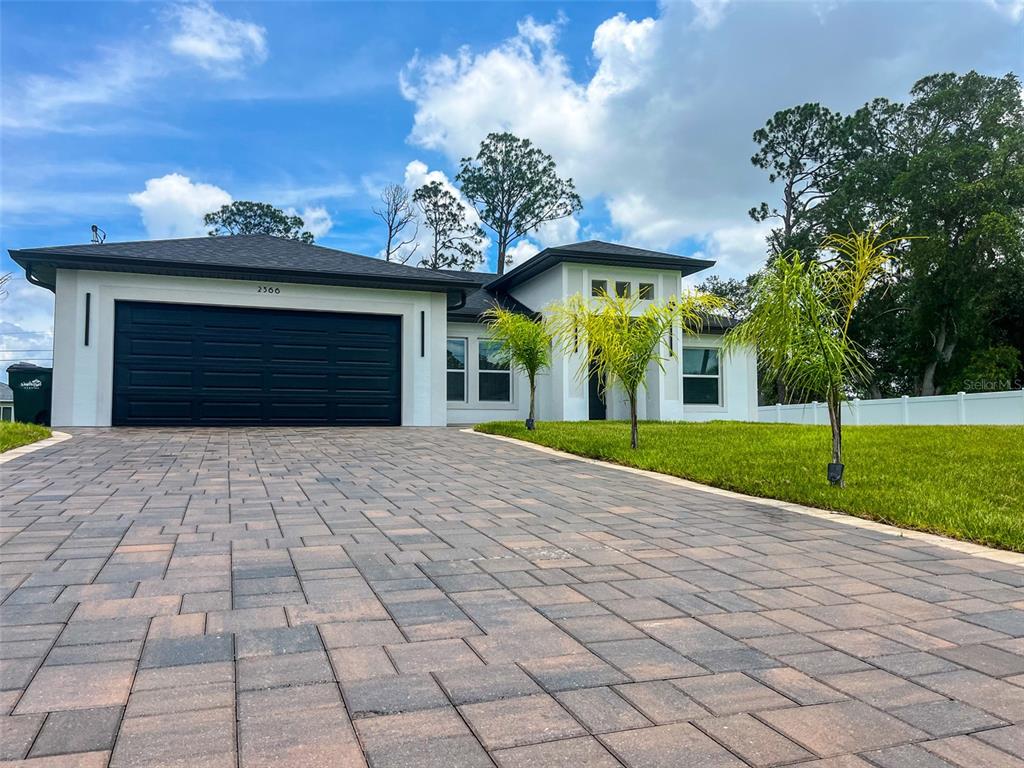 A single-story house with a white exterior, black garage door, and a paved driveway — 2366 RIBBLE STREET, NORTH PORT, FL