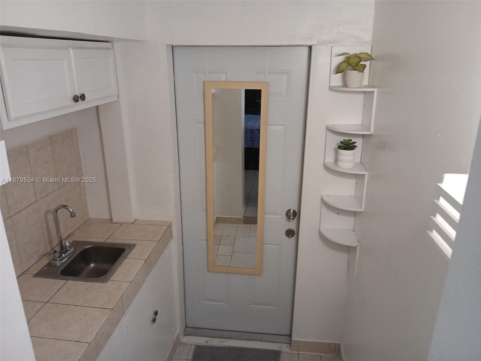 A small kitchen area features a sink, white cabinets, a door with a mirror, and shelves — 11510 SW 182nd Ter # 2, Miami FL 33157, MIAMI, FL