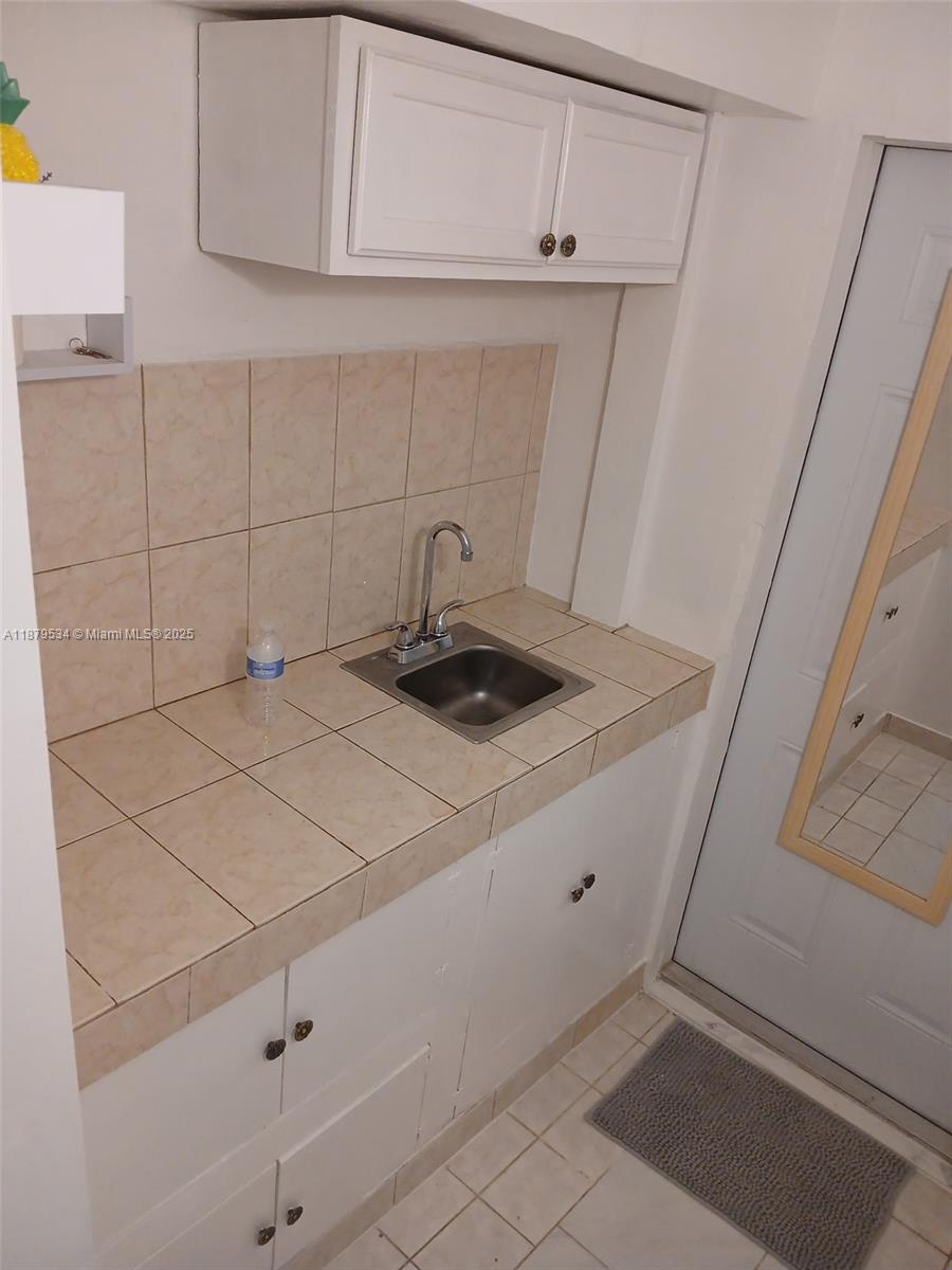 A small kitchen features white cabinets, a tiled countertop, and a stainless steel sink — 11510 SW 182nd Ter # 2, Miami FL 33157, MIAMI, FL