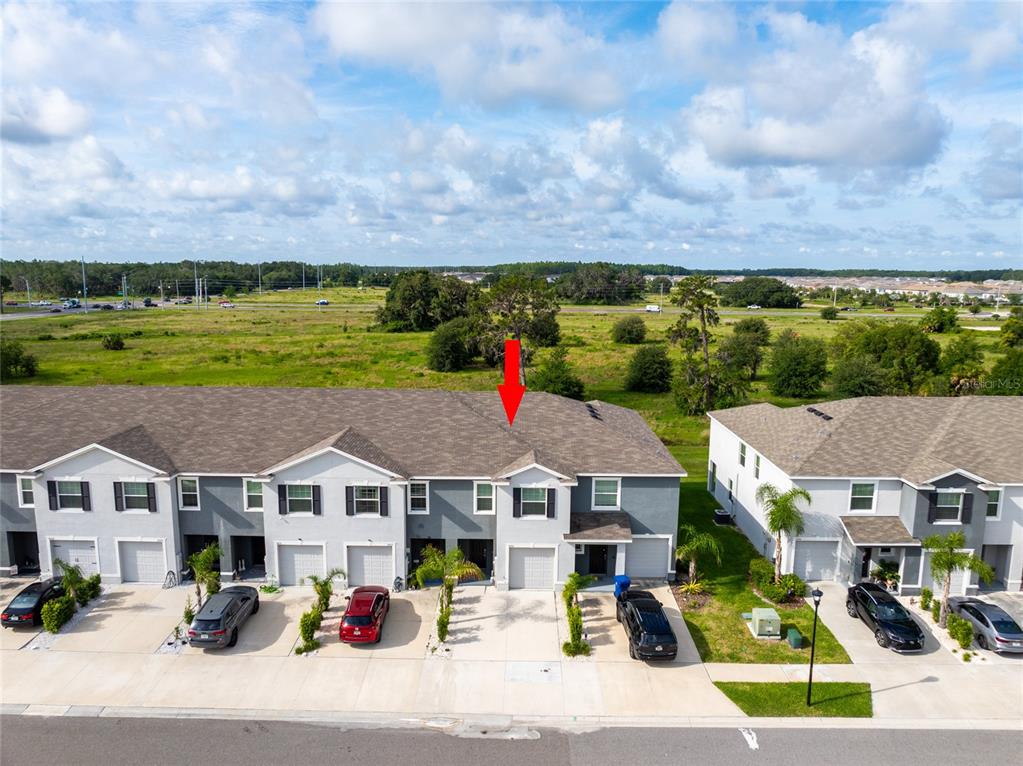 An aerial view of a multi-unit townhouse complex with a red arrow pointing to one unit — 34310 REDWOOD DAWN LANE, WESLEY CHAPEL, FL