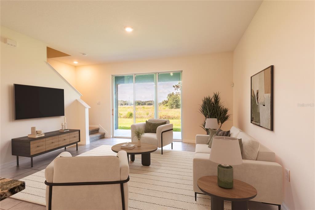 A living room features a television, sofa, two armchairs, a coffee table, and sliding glass doors — 34310 REDWOOD DAWN LANE, WESLEY CHAPEL, FL