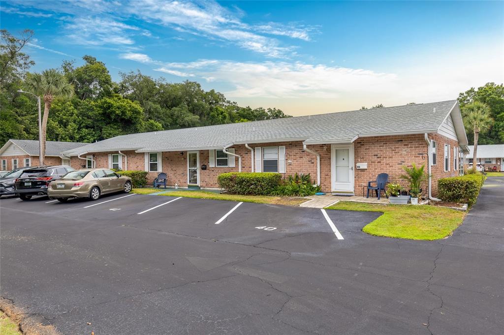 A single-story brick apartment building features a parking lot in front and green landscaping — 41 FAIRWAY COURT UNIT 41, DELAND, FL