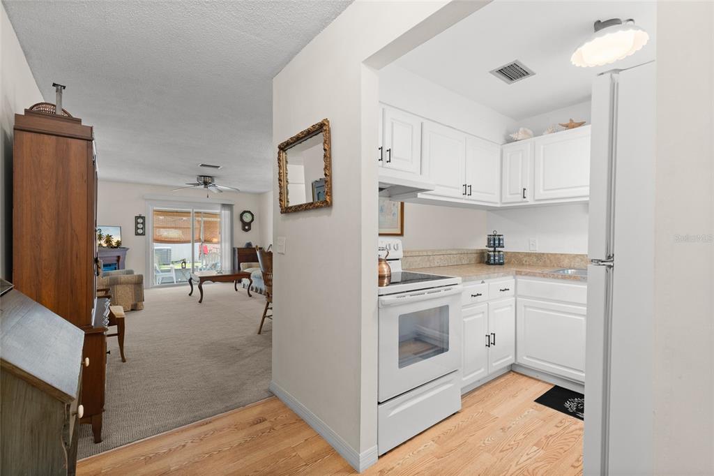A view from a hardwood-floored kitchen into a carpeted living room with a sliding door — 41 FAIRWAY COURT UNIT 41, DELAND, FL