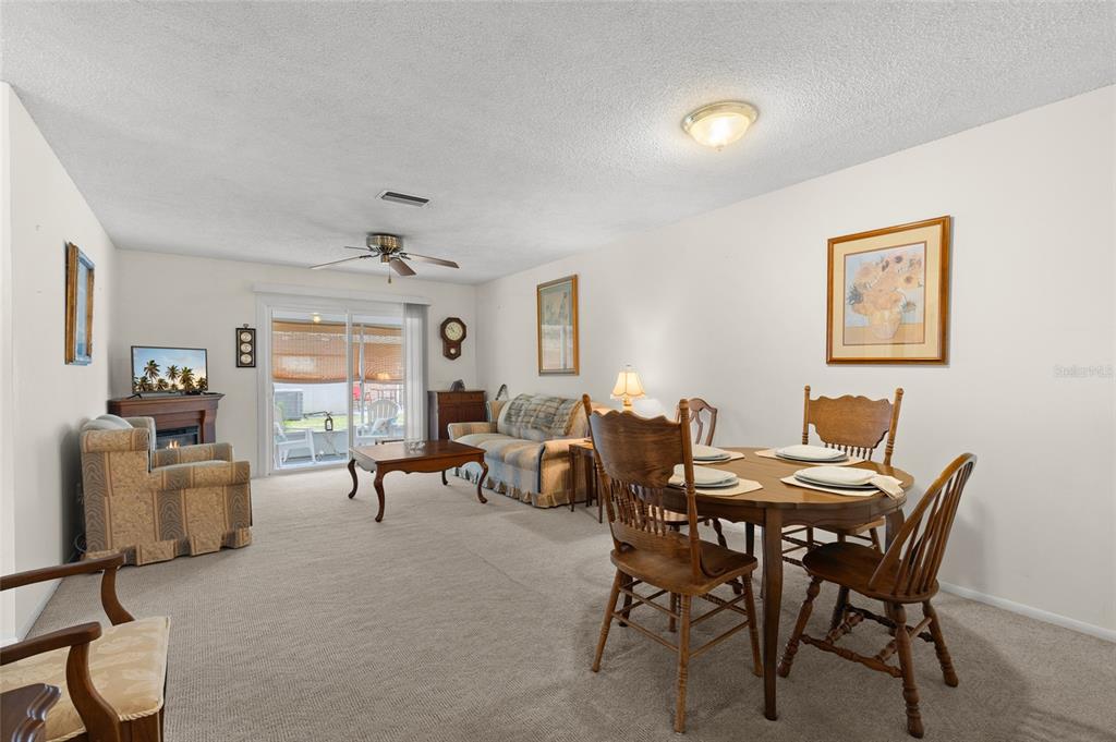A living and dining room with carpeted floors, a ceiling fan, and a sliding glass door — 41 FAIRWAY COURT UNIT 41, DELAND, FL