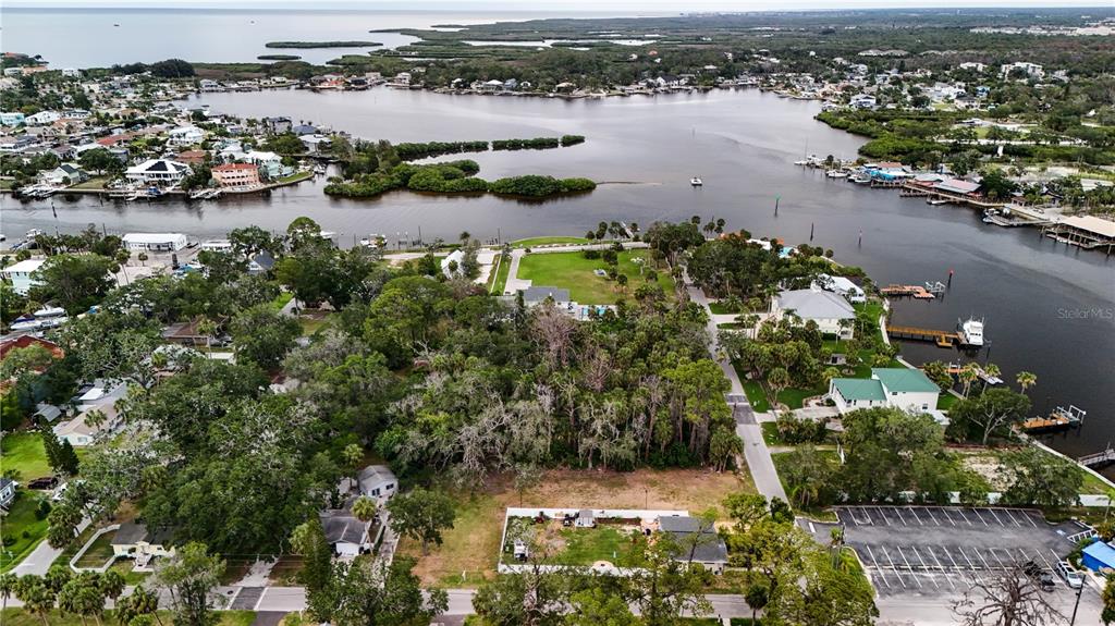 An aerial view shows a coastal neighborhood with houses, dense trees, and a waterway — 7751 PIER ROAD, PORT RICHEY, FL