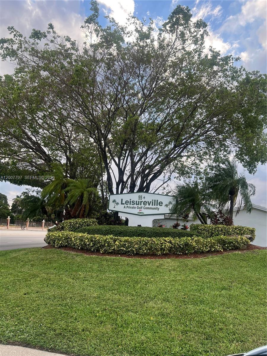 A sign for Leisureville, a 55+ private golf community, stands in front of a large tree — 2501 W Golf Blvd # 128, Pompano Beach FL 33064, POMPANO BEACH, FL