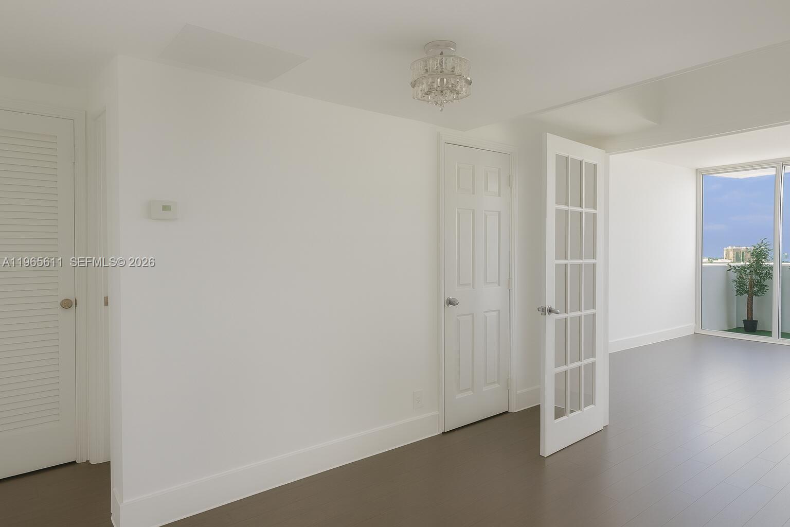 A room with white walls, dark flooring, a crystal light fixture, and a glass door — 1200 West Ave # 1507, Miami Beach FL 33139, MIAMI BEACH, FL