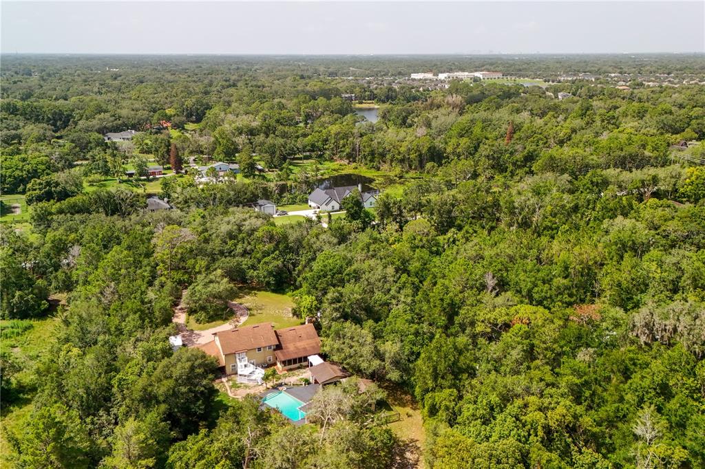 An aerial view shows a house with a pool surrounded by dense forest and trees — 230 E PANAMA ROAD, WINTER SPRINGS, FL