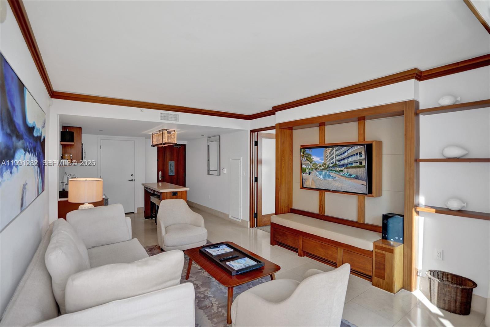 A living room features cream-colored seating, a wooden media console, and built-in wall shelving — 6801 Collins Ave # 314, Miami Beach FL 33141, MIAMI BEACH, FL