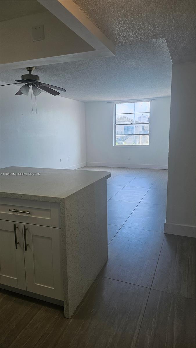 A kitchen island with white cabinets and a light countertop overlooks an open living area — 5625 W 20th Ave # 208, Hialeah FL 33012, HIALEAH, FL