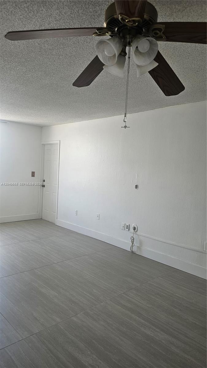 An empty room features gray wood-look tile flooring, white walls, and a ceiling fan — 5625 W 20th Ave # 208, Hialeah FL 33012, HIALEAH, FL