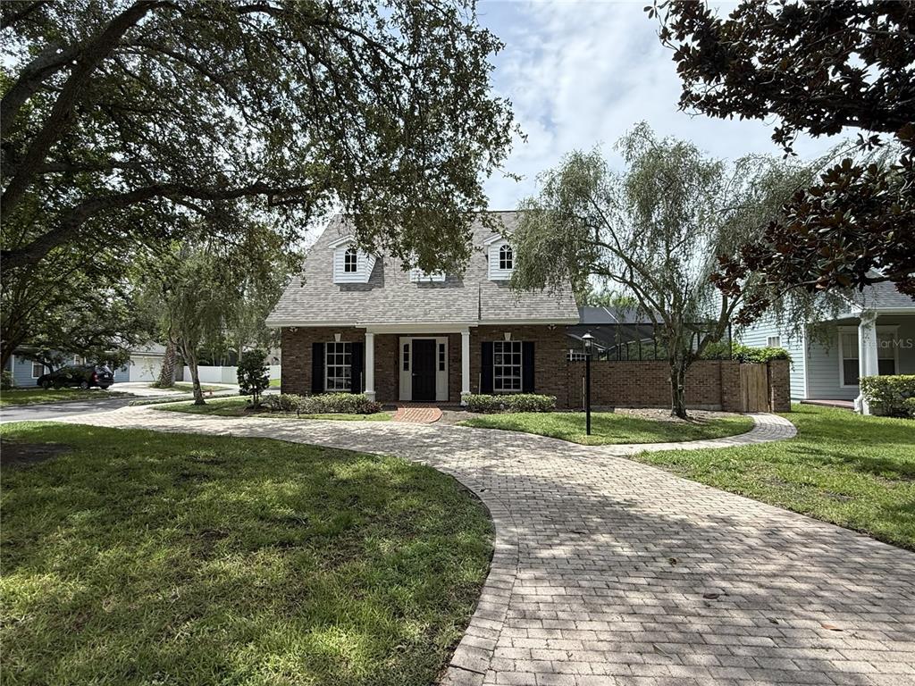 A two-story brick house features a curved paver driveway and three dormer windows — 4002 W DALE AVENUE, TAMPA, FL