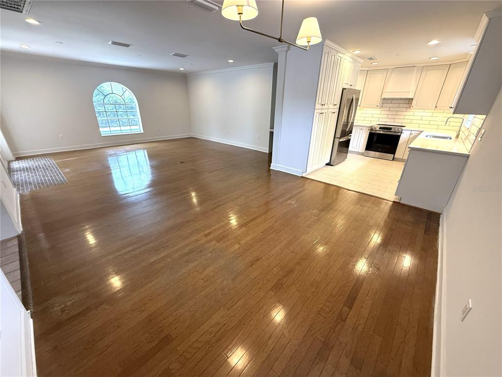 An open-concept room features hardwood floors, a white kitchen, and an arched window — 4002 W DALE AVENUE, TAMPA, FL