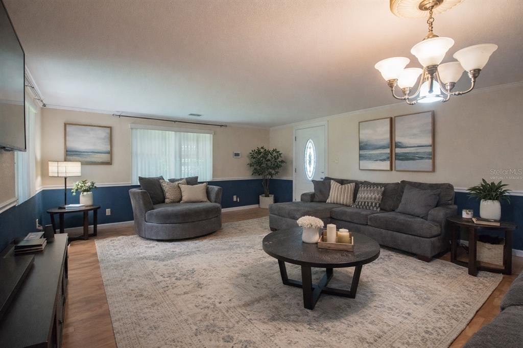 A living room with blue and cream walls, a gray sectional, and a round chair — 7893 S US HIGHWAY 441, LAKE CITY, FL