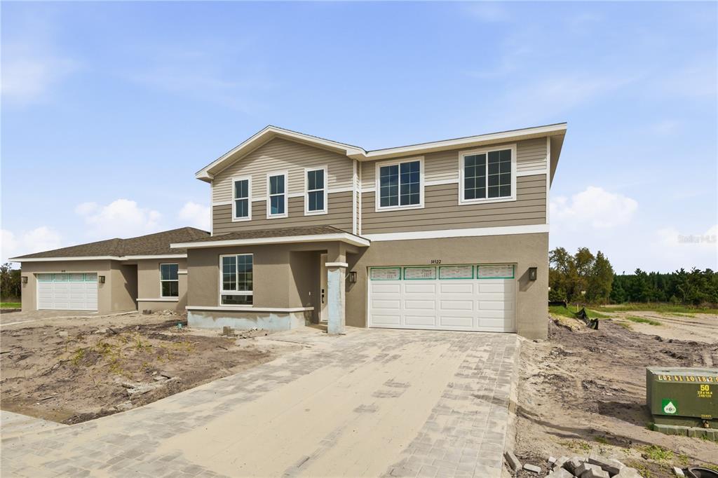A two-story house with tan siding, a stucco lower level, and a paved driveway — 14522 BANKS COURT, PARRISH, FL