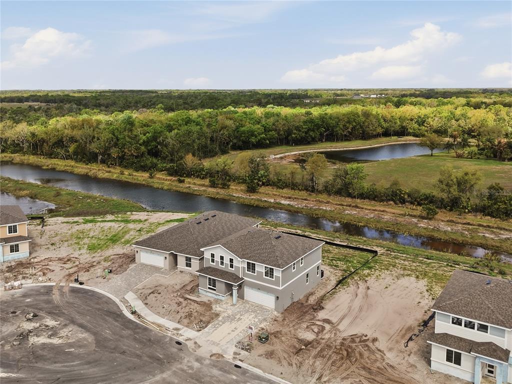 An aerial view shows a newly constructed two-story house near a canal and woods — 14522 BANKS COURT, PARRISH, FL