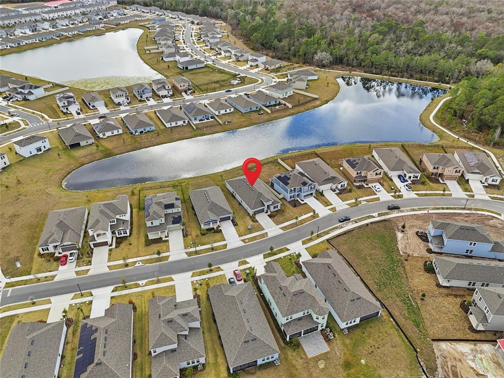 An aerial view shows a suburban neighborhood with houses surrounding a central pond — 4698 CORAL HARBOUR ROAD, KISSIMMEE, FL