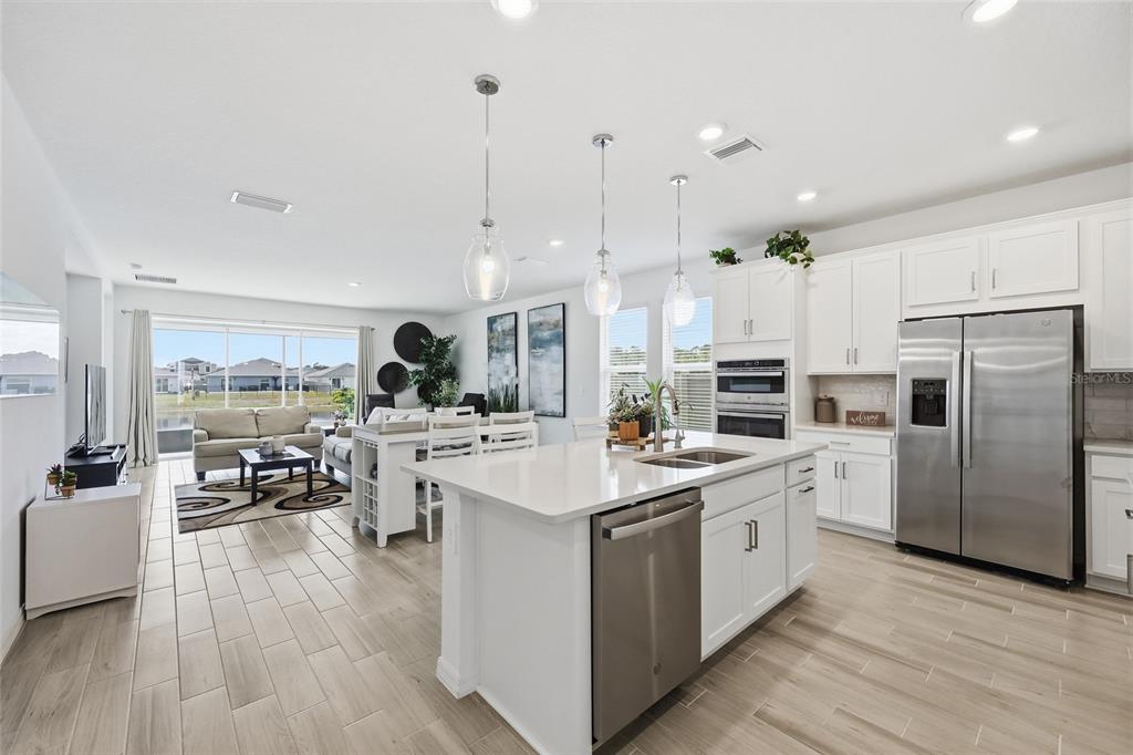 A modern open-concept kitchen with white cabinets, stainless steel appliances, and a central island — 4698 CORAL HARBOUR ROAD, KISSIMMEE, FL