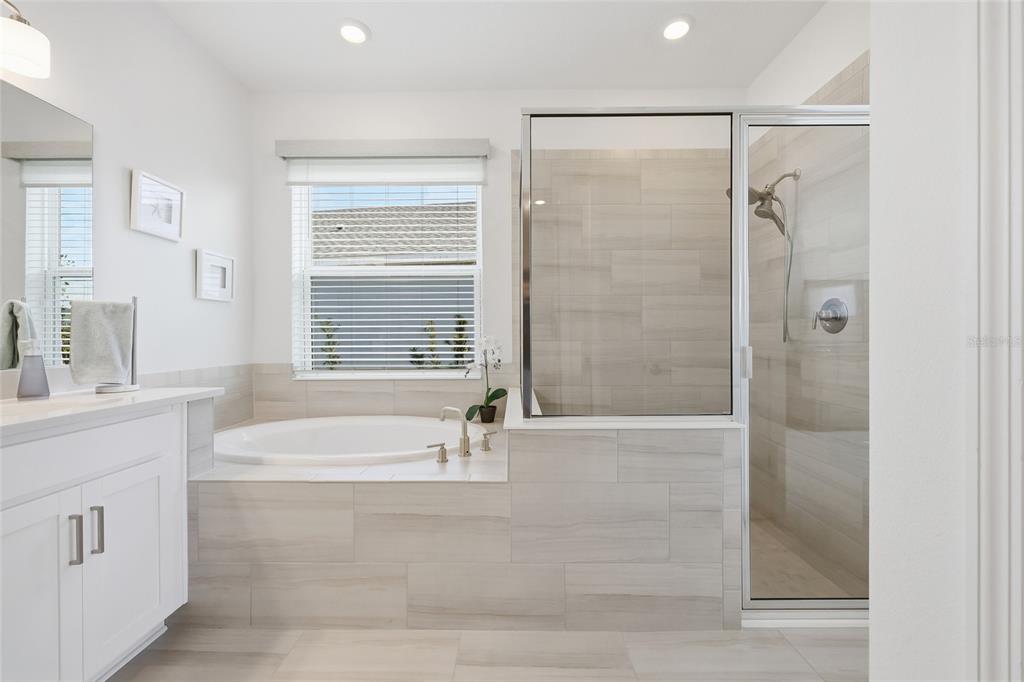 A bathroom featuring a white vanity, a soaking tub, and a glass-enclosed walk-in shower — 4698 CORAL HARBOUR ROAD, KISSIMMEE, FL