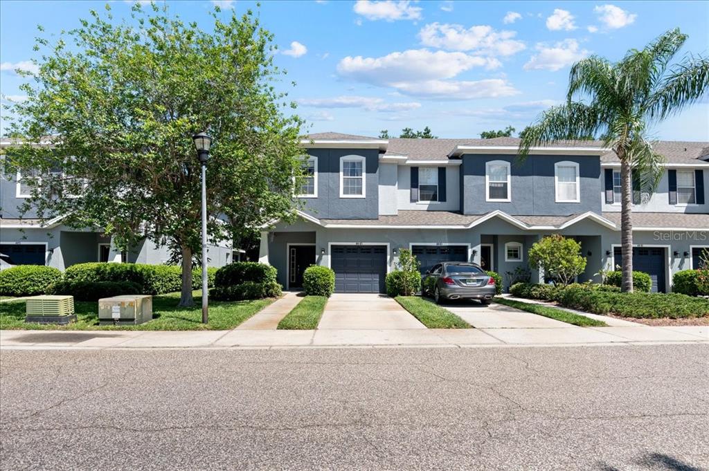 A row of two-story townhomes with gray siding, attached garages, and manicured landscaping — 4445 AMBERLY OAKS COURT, TAMPA, FL
