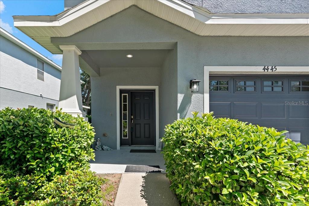 The exterior of a house features a gray garage, a front door, and green bushes — 4445 AMBERLY OAKS COURT, TAMPA, FL