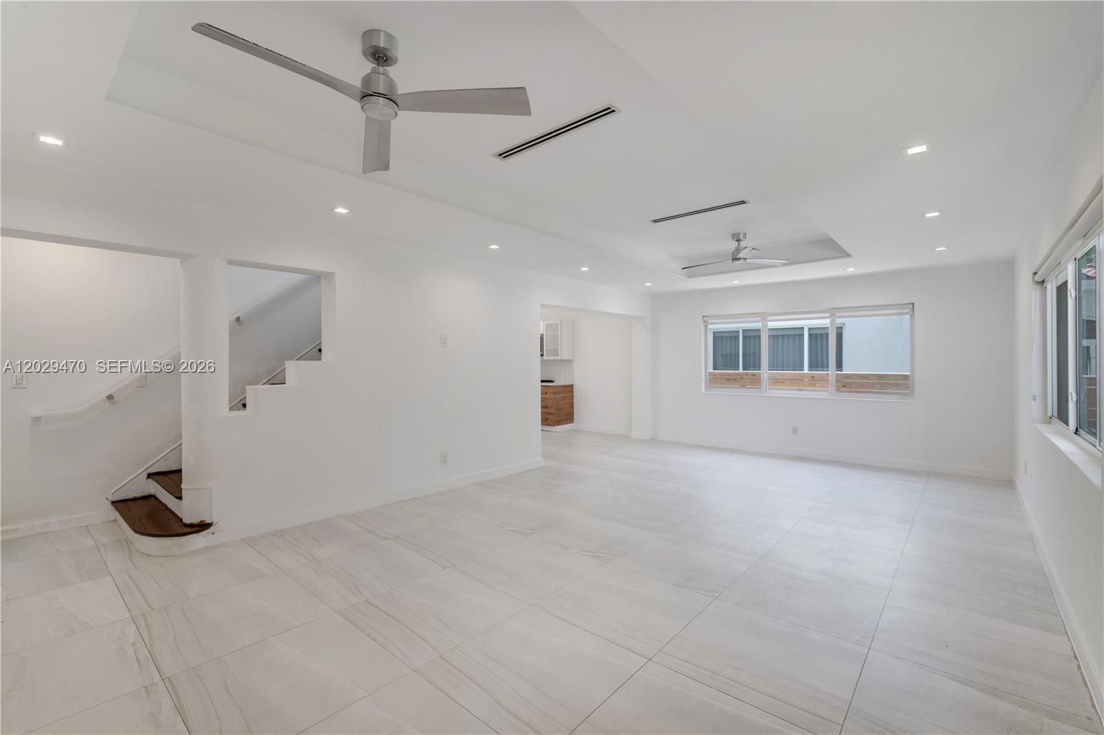 A bright, open-concept living area features white tile floors, recessed lighting, ceiling fans, and stairs — 550 W 49th St, Miami Beach FL 33140, MIAMI BEACH, FL