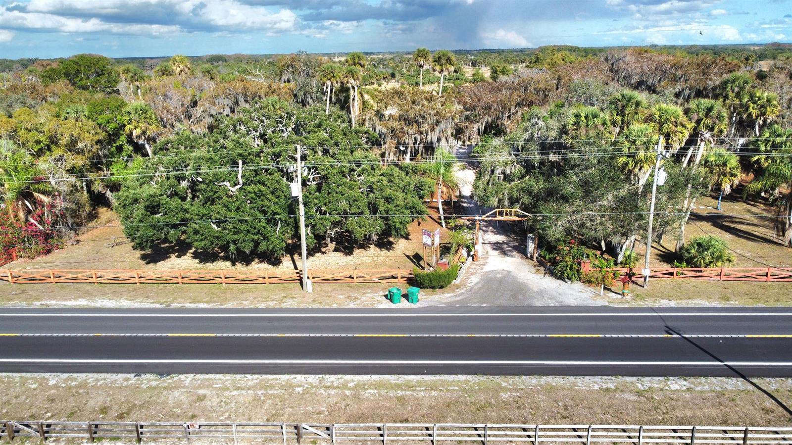 An aerial view shows a gravel driveway entrance with a wooden gate off a road — 12963 Us Hwy 441 SE, Okeechobee FL 34974, OKEECHOBEE, FL