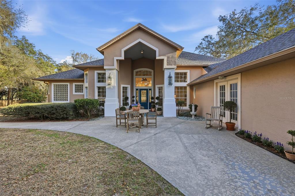 A beige house with a covered entryway, concrete patio, and a blue front door — 6197 LAKE WINONA ROAD, DE LEON SPRINGS, FL