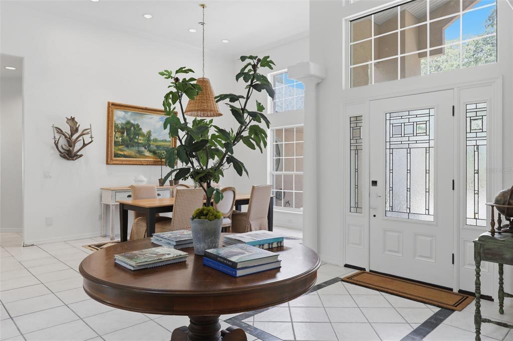 A bright foyer features a round wooden table, a large potted plant, and a front door — 6197 LAKE WINONA ROAD, DE LEON SPRINGS, FL