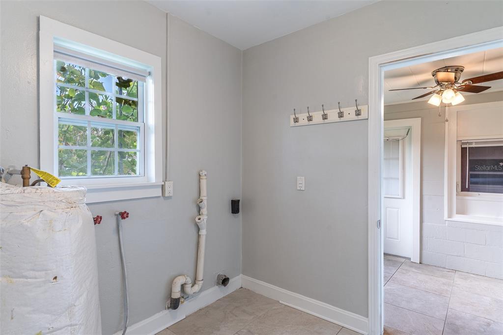 A laundry room features a window, utility plumbing, a wall-mounted coat rack, and tiled floors — 916 COHASSETT AVENUE, LAKE WALES, FL