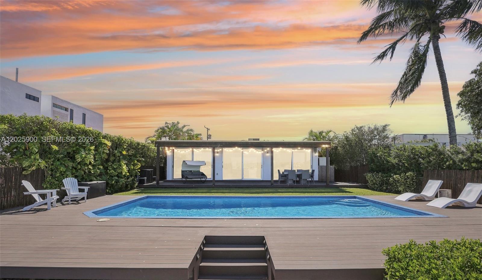 A rectangular swimming pool sits in front of a modern house with a wooden deck — 1231 Stillwater Dr, Miami Beach FL 33141, MIAMI BEACH, FL